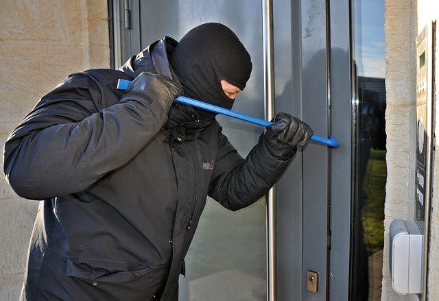 man forcing a door open with a crowbar