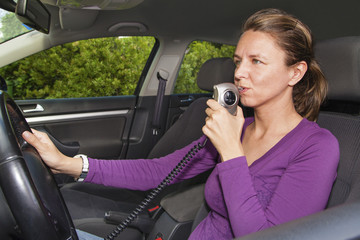 woman blowing into ignition interlock device in car