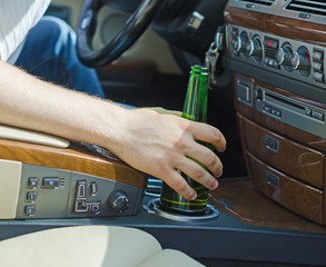 man putting beer in cupholder in car