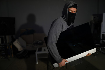 man in ski mask committing larceny stealing tv