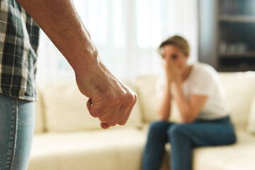 man's clenched fist with woman in background