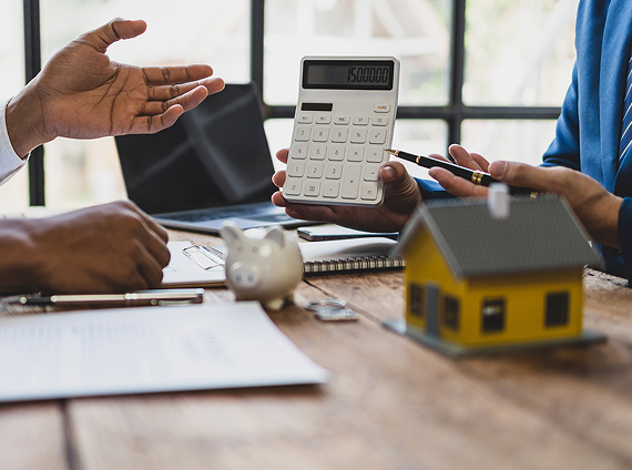 model of a house on a desk with a calculator